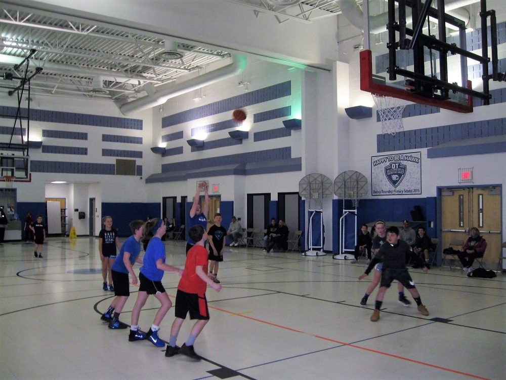 Kids playing basketball game in gymnasium
